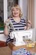 Old woman sews on the sewing machine