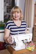Old woman sews on the sewing machine