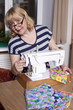 Old woman sews on the sewing machine