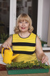 Happy senior woman watering can at home