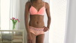 Black woman in lingerie standing by window