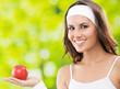 Photo: Woman in fitness wear with apple, outdoors Woman in fitness wear with apple, outdoors