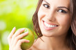 Young happy smiling woman with apple, outdoors