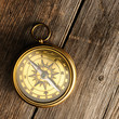 Antique compass over wooden background