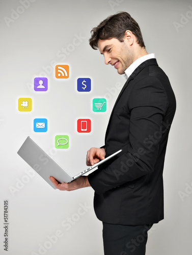 Photo: Business man with laptop in hand and media icon Business man with laptop in hand and media icon