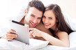 Couple in bed using digital tablet