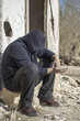 Homeless person begging near the destroyed  house