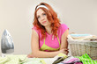 Young beautiful woman ironing clothes in room on grey
