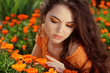 Young woman outdoors portrait over orange marigold flowers