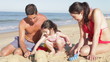 Family Building Sandcastle On Beach