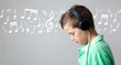 Handsome teen boy listening to music on headphones over grey bac