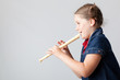 Image of schoolgirl playing the flute on a grey background