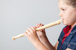 Image of schoolgirl playing the flute on a grey background