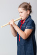 Image of schoolgirl playing the flute on a grey background