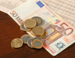 Money: euro coins and bills close up isolated on wood background