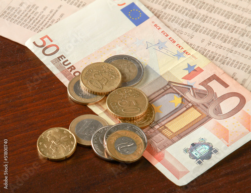 Photo: Money: euro coins and bills close up isolated on wood background Money: euro coins and bills close up isolated on wood background