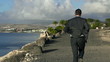 Young businessman jogging on the seashore, slow motion shot 60