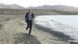 Young businessman jogging on the seashore with cellphone, slow m