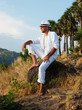 Foto: a young man sitting on a rock and looking at the sunset a young man sitting on a rock and looking at the sunset