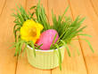 Easter egg in bowl with grass on wooden table close up
