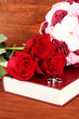 Wedding rings on bible with roses on wooden background