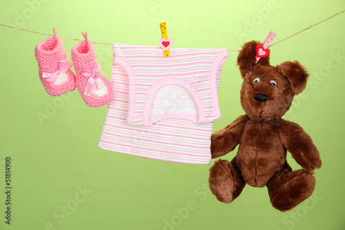 Photo: Baby clothes hanging on clothesline, on color background Baby clothes hanging on clothesline, on color background