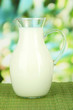 Pitcher of milk on table on bright background