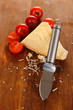 Piece of Parmesan cheese with knife on wooden table close-up