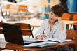Young businesswoman with laptop at a sidewalk cafe