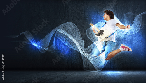 Photo: young man playing on electro guitar and jumping young man playing on electro guitar and jumping