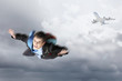 Young businessman flying with parachute on back