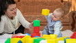 mother playing with her baby boy in bright geometric blocks