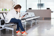 Photo: Tired Caucasian woman with devices sitting in airport lounge Tired Caucasian woman with devices sitting in airport lounge