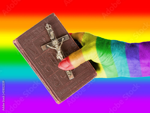 Photo: Old hand (woman) holding a very old bible, rainbow flag Old hand (woman) holding a very old bible, rainbow flag