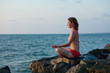 Woman that meditates at the sea during sunset
