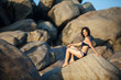 Photo: Woman in swimsuit takes rest at huge rocks the sea shore Woman in swimsuit takes rest at huge rocks the sea shore