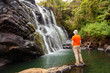 Trekker looks at wild waterfall in Horton Plains National Park,