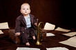Caucasian baby boy plays with trumpet between sheets with musica