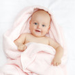 Foto: Caucasian baby boy covered with pink towel joyfully smiles at ca Caucasian baby boy covered with pink towel joyfully smiles at ca