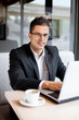 smiling businessman sitting at desk with laptop