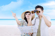 Asian couple using binoculars on beach