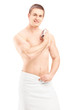 Handsome young man in towel spraying perfume