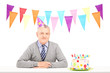 Happy mature gentleman with party hat and a birthday cake