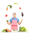 Male with apron juggling with vegetables while preparing food