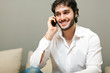 Young man smiling and talking on smart phone at home