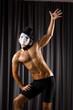 Muscular actor with mask against curtain