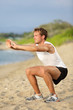 Fitness man training air squat exercise on beach