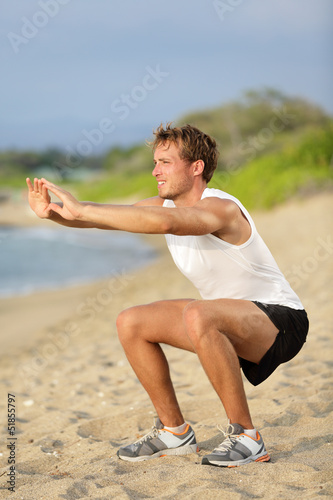Photo: Fitness man training air squat exercise on beach Fitness man training air squat exercise on beach