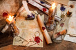 Antique table filled with old papers, red sealant and candles