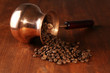 Coffee pot with coffee beans on brown wooden background